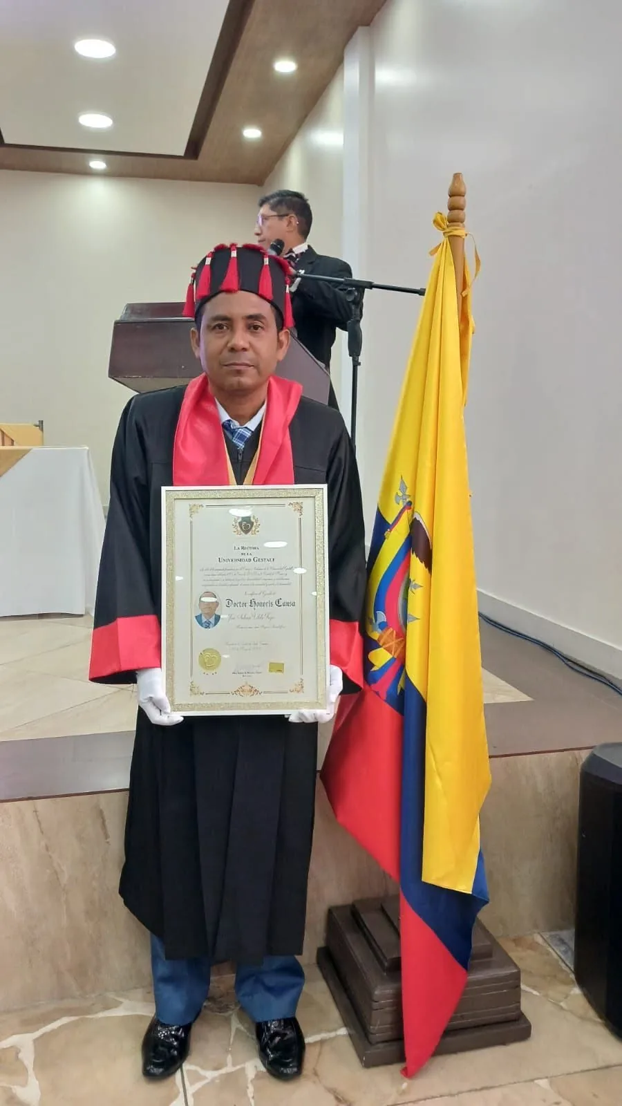 El Dr. José Antonio Vilela Trejo junto a la bandera de Ecuador en la ceremonia
